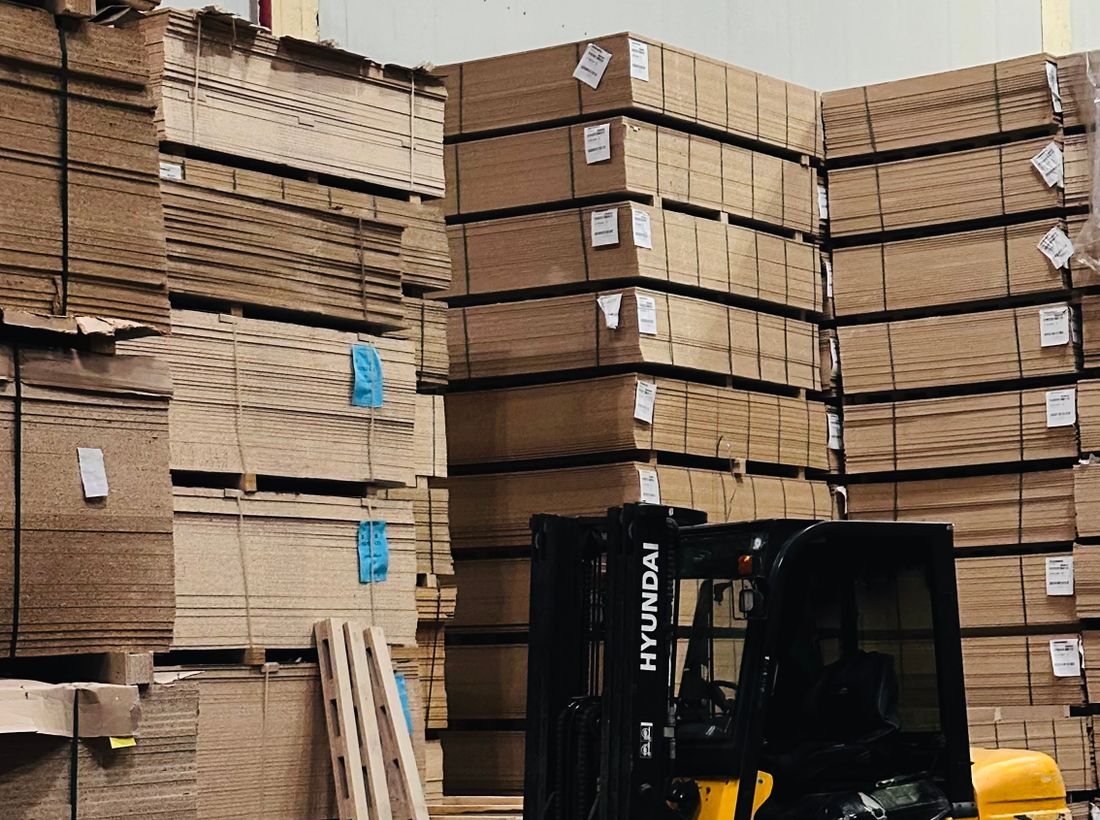 Forklift moving stacked board in a warehouse